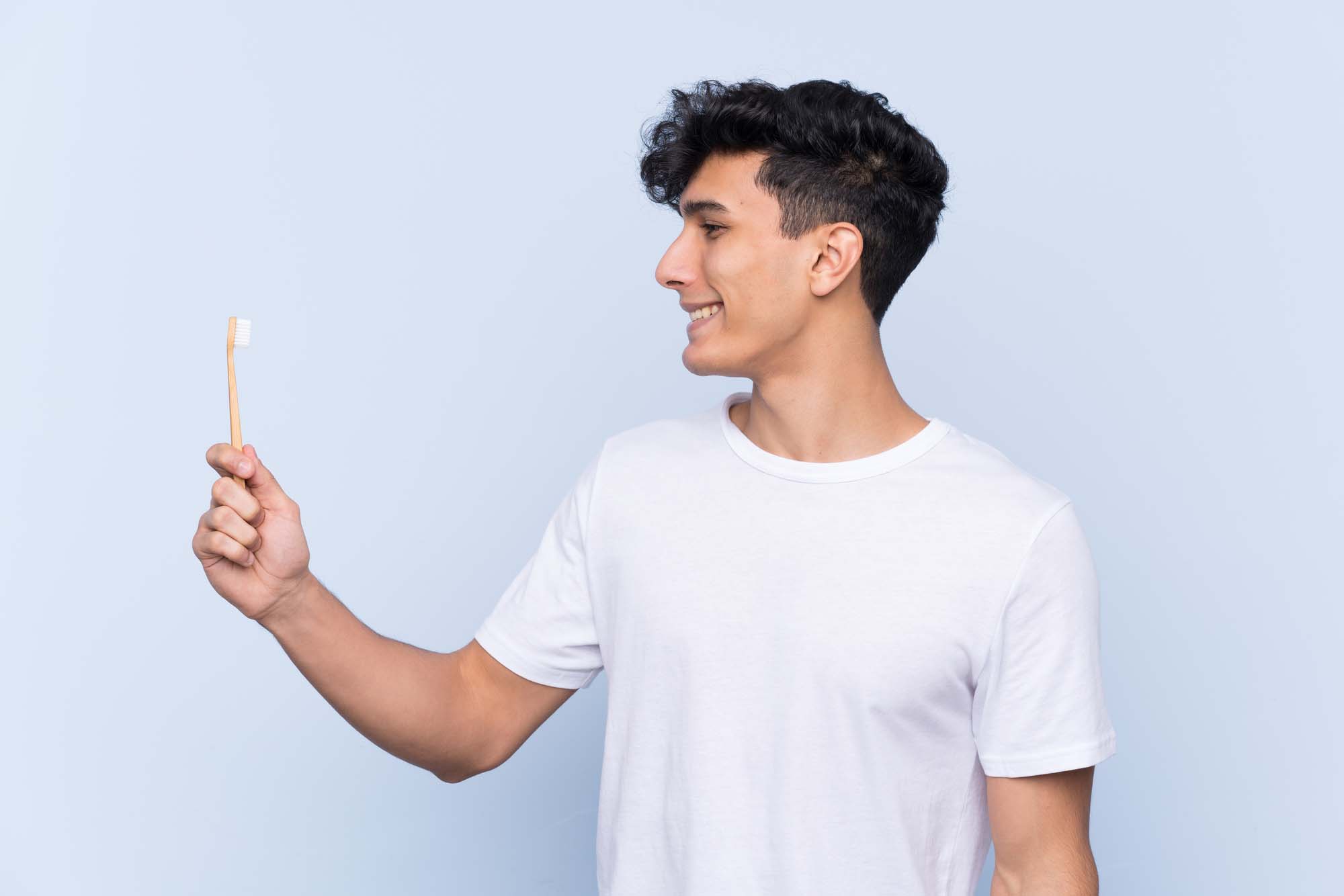 Young Argentinian man brushing his teeth over isolated blue background with happy expression Dental Clinic Ottawa Ontario