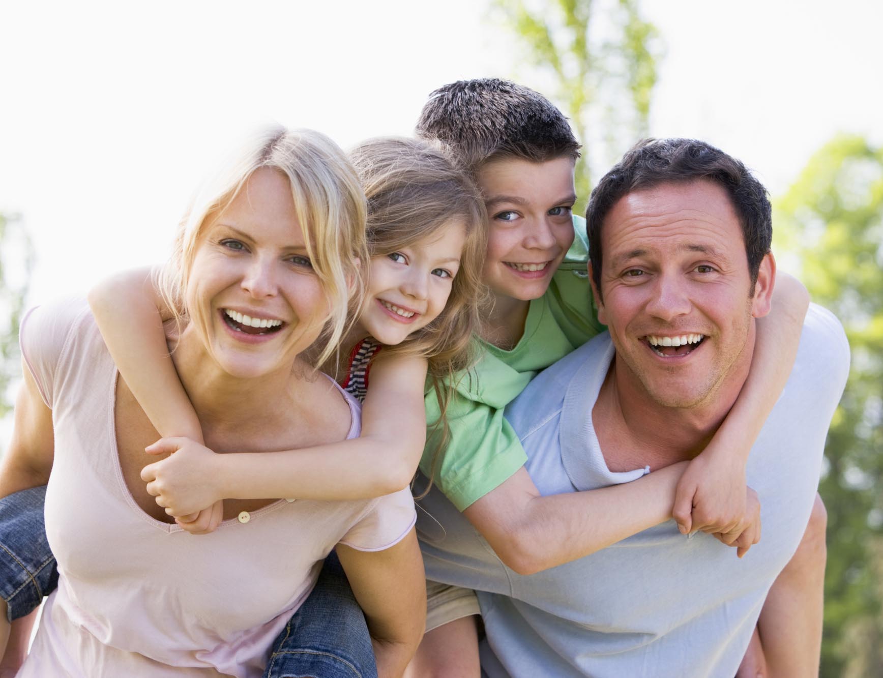 Couple giving two young children piggyback rides smiling Top Rated Dentist in Ottawa Ontario